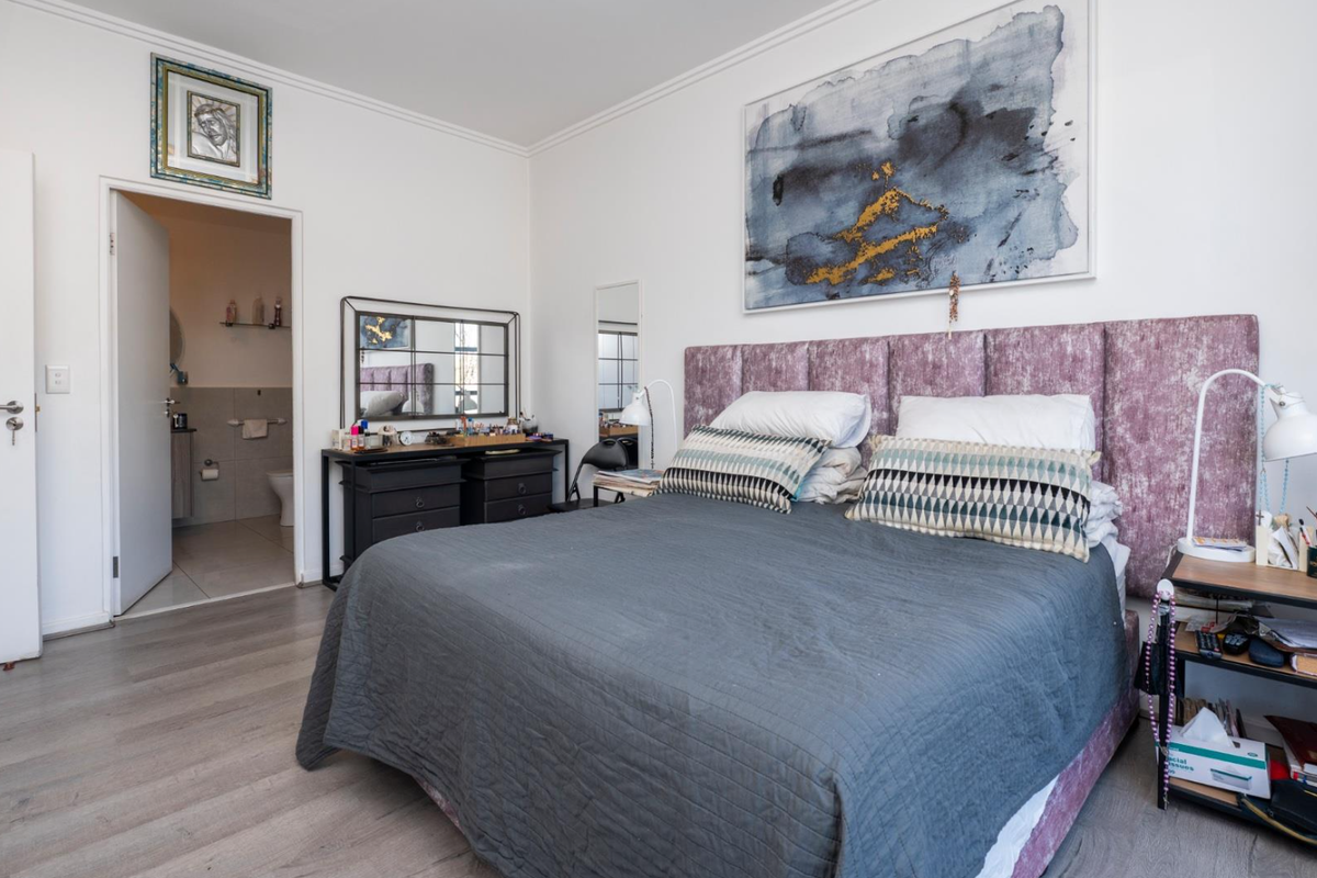 A well-maintained bedroom featuring laminate flooring, coving, and direct access to an en-suite bathroom.