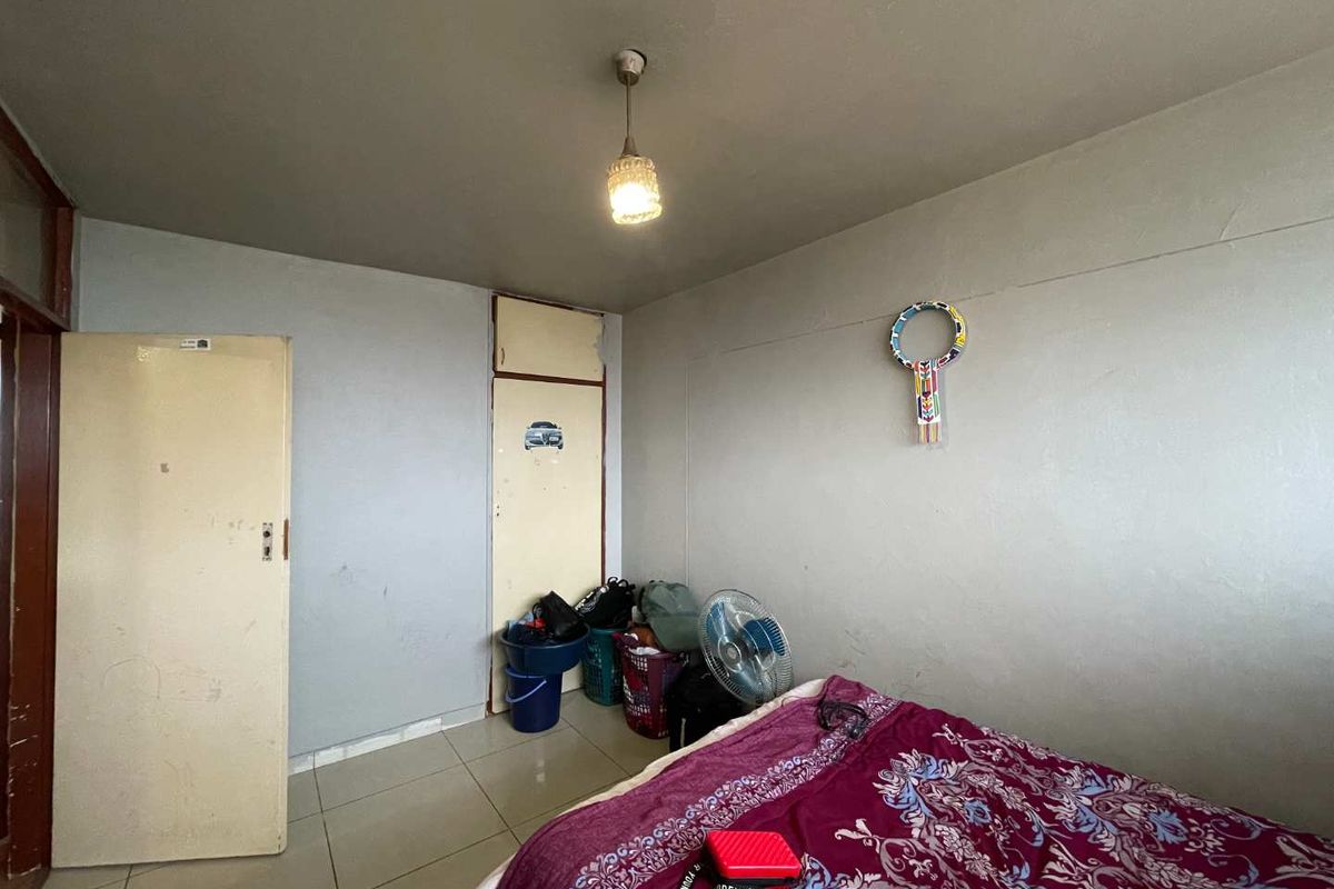 A bedroom featuring tiled flooring and a built-in cupboard with overhead storage.