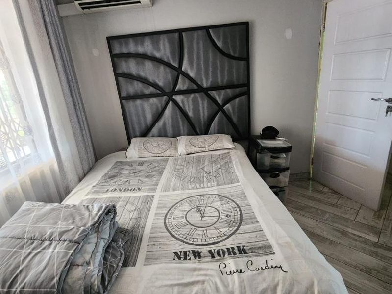 A bedroom featuring tiled flooring, a wall-mounted air conditioning unit, and neutral wall finishes with minor maintenance required.