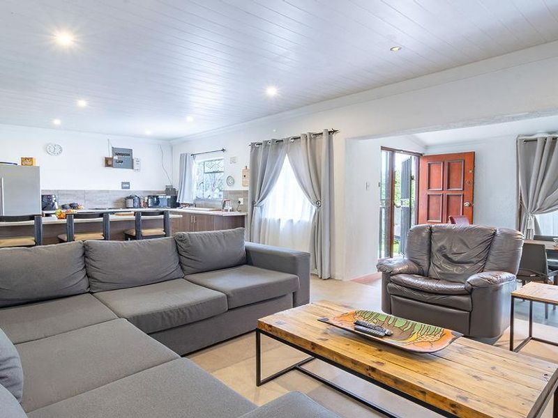 Spacious open-plan living area featuring a modern kitchen with island, recessed lighting, and seamless flow to the outdoor entrance.