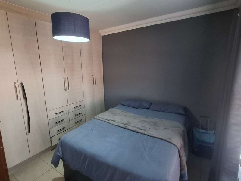 A well-maintained bedroom featuring extensive built-in cupboards, tiled flooring, and neutral wall finishes, providing ample storage and a comfortable living space.