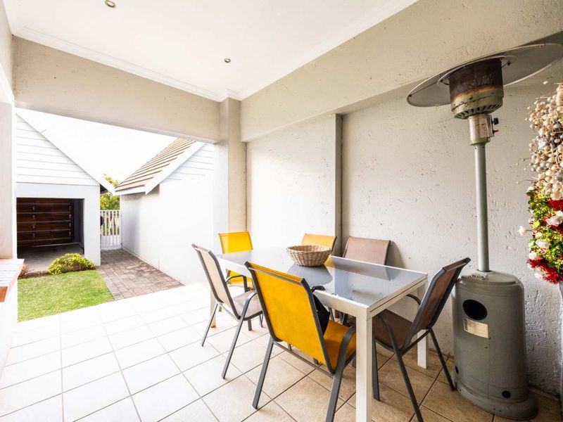 A covered patio area featuring tiled flooring and recessed lighting, providing a functional outdoor space for dining and relaxation.