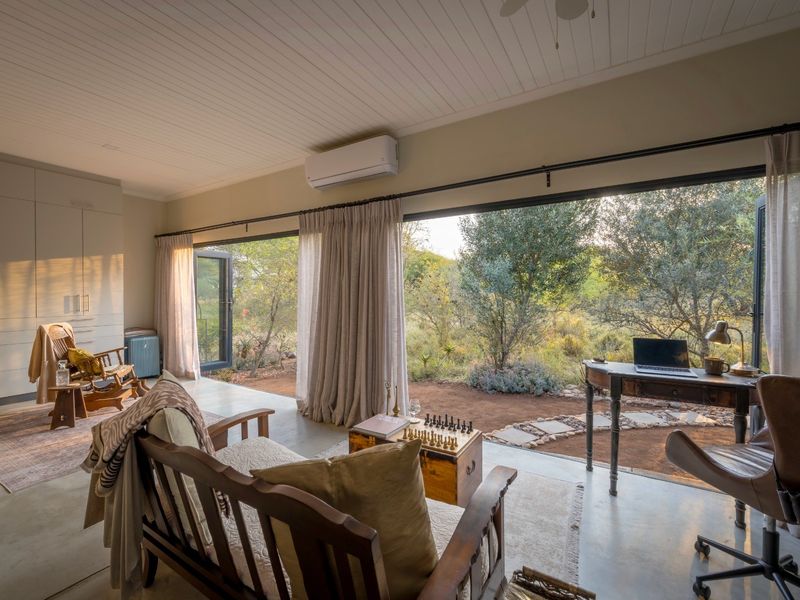 Spacious living area featuring polished concrete floors, built-in cabinetry, and large sliding glass doors that open to a natural bushveld landscape.