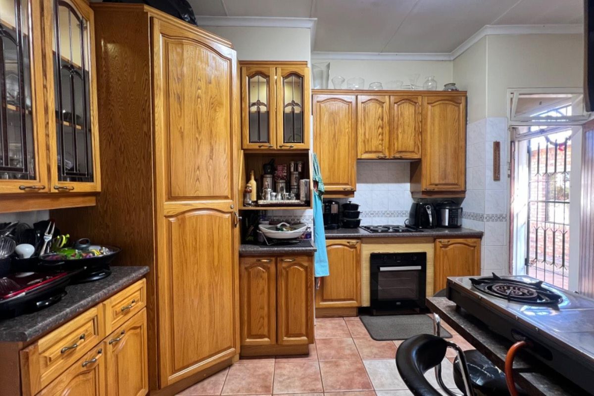 A traditional kitchen featuring extensive oak-style cabinetry, built-in oven, gas hob, and tiled flooring with direct access to an outdoor area.