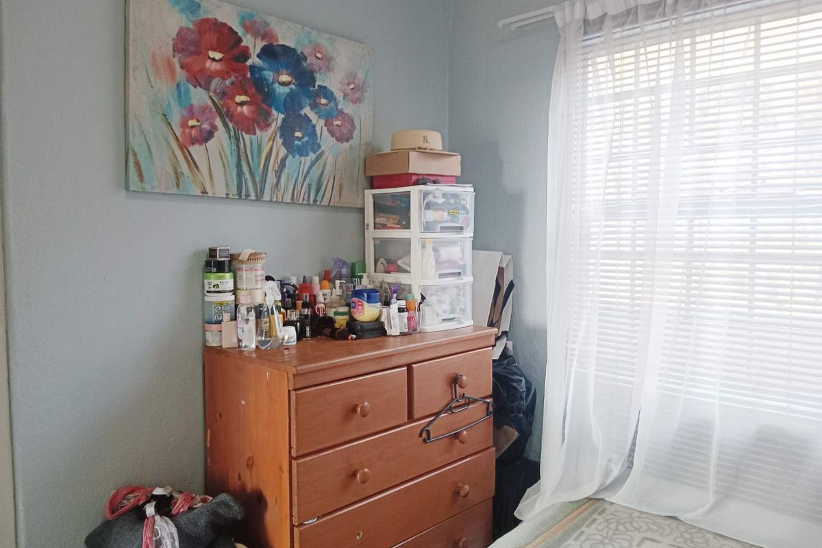 A bedroom corner featuring a window with installed blinds and curtain rod, providing natural light to the space.