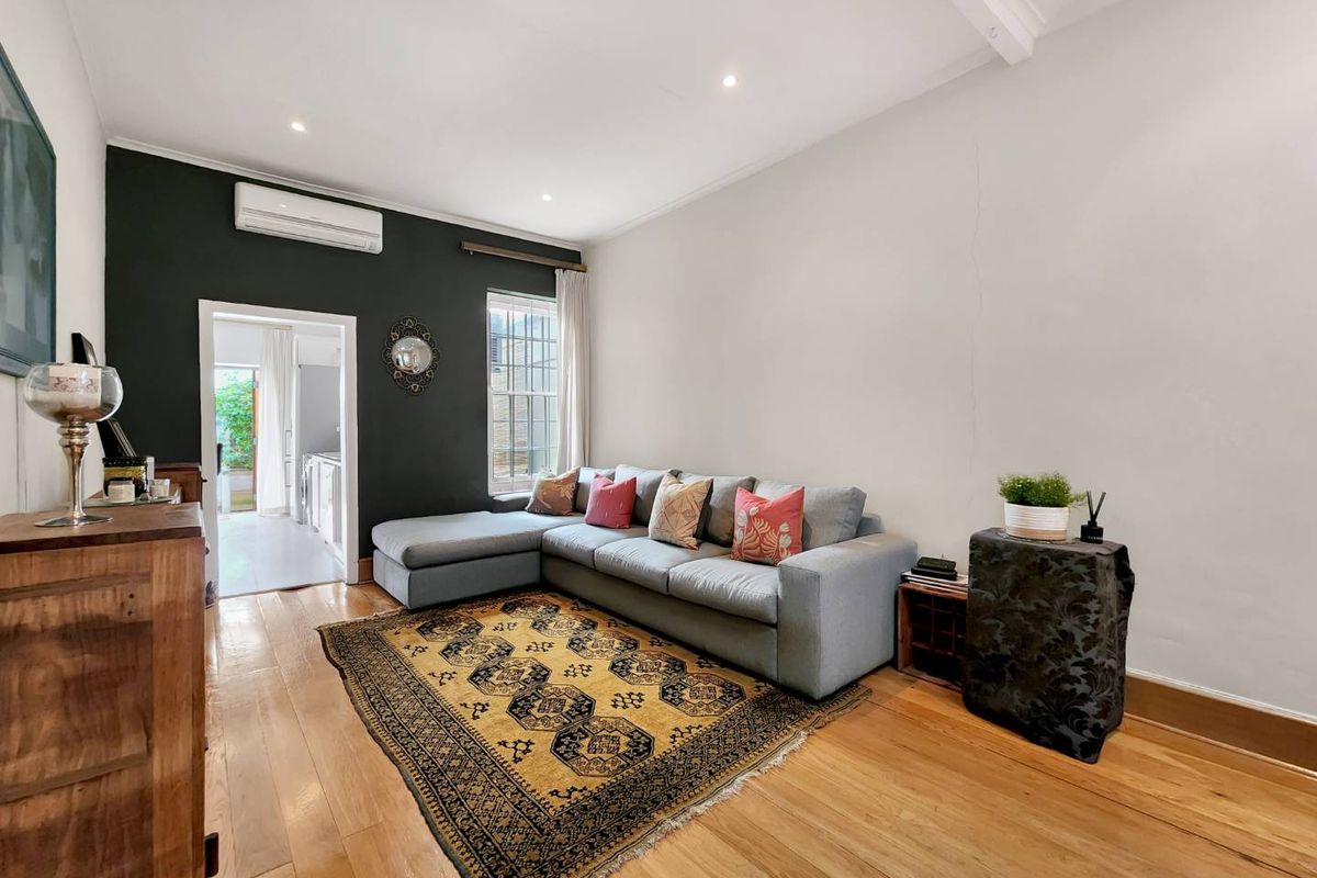 A living room featuring hardwood flooring, recessed lighting, and a split-system air conditioner, with a view through to an adjacent utility area.