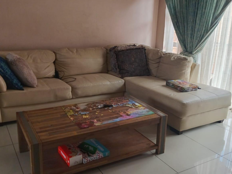 A living room area featuring light-colored tiled flooring and access to a balcony through a large sliding glass door.