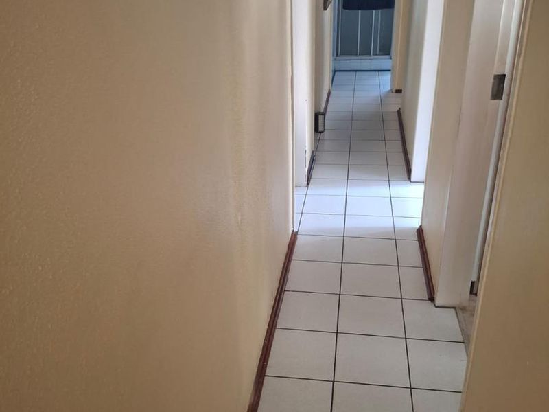 A functional hallway featuring tiled flooring and a central ceiling light fixture, providing access to adjacent rooms.