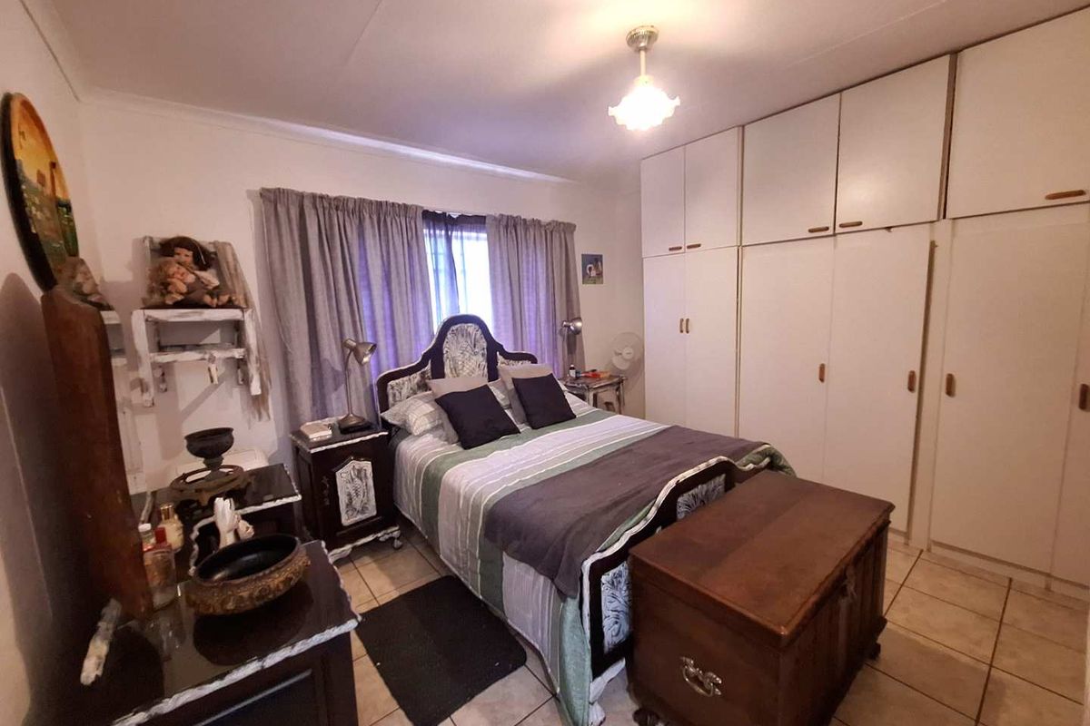 A bedroom featuring built-in floor-to-ceiling wardrobes and tiled flooring.