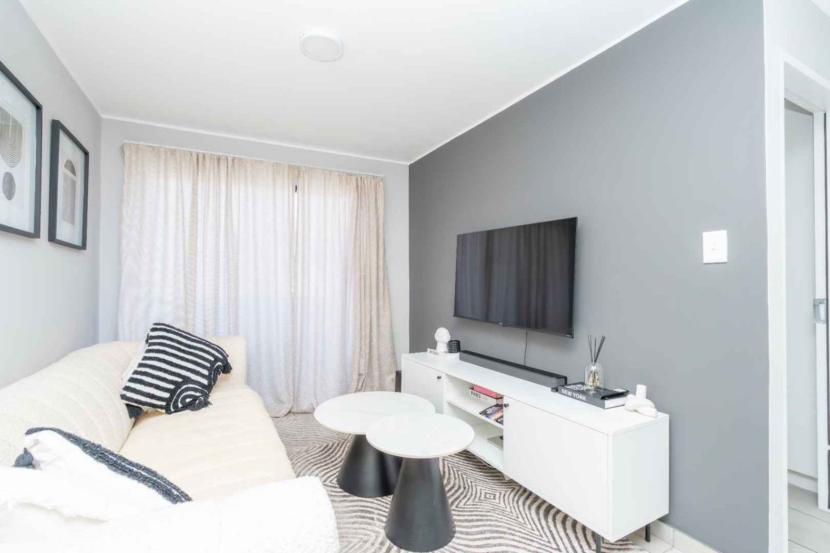 A modern living room featuring a neutral grey accent wall, tiled flooring, and large sliding glass doors providing natural light.