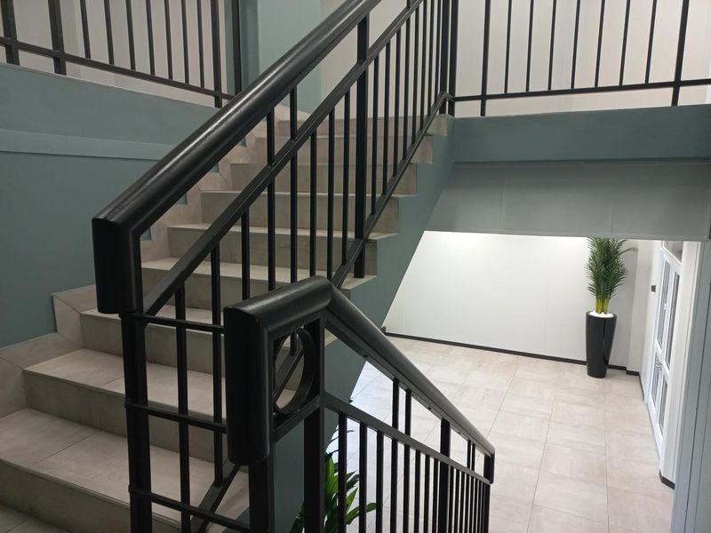 A modern office building interior featuring a tiled staircase with black metal railings and neutral-toned wall finishes.