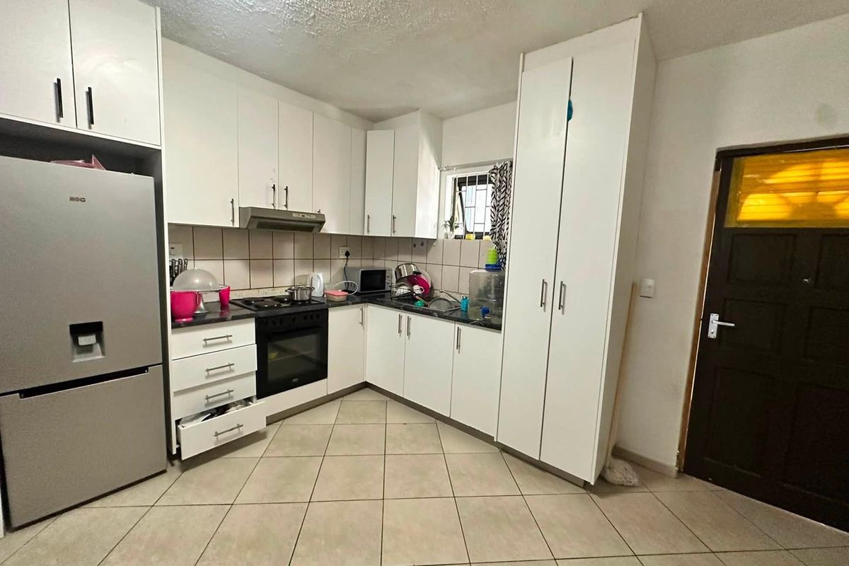 A functional kitchen featuring white built-in cabinetry, a tiled backsplash, integrated oven and hob, and tiled flooring.
