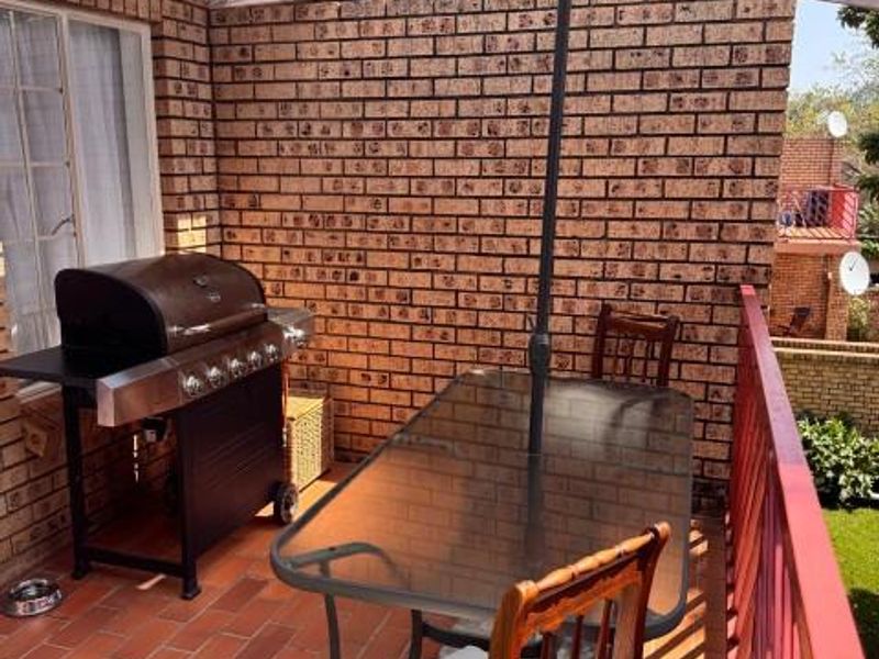 A private balcony featuring exposed brick walls, tiled flooring, and a metal safety railing, providing an outdoor space for relaxation.