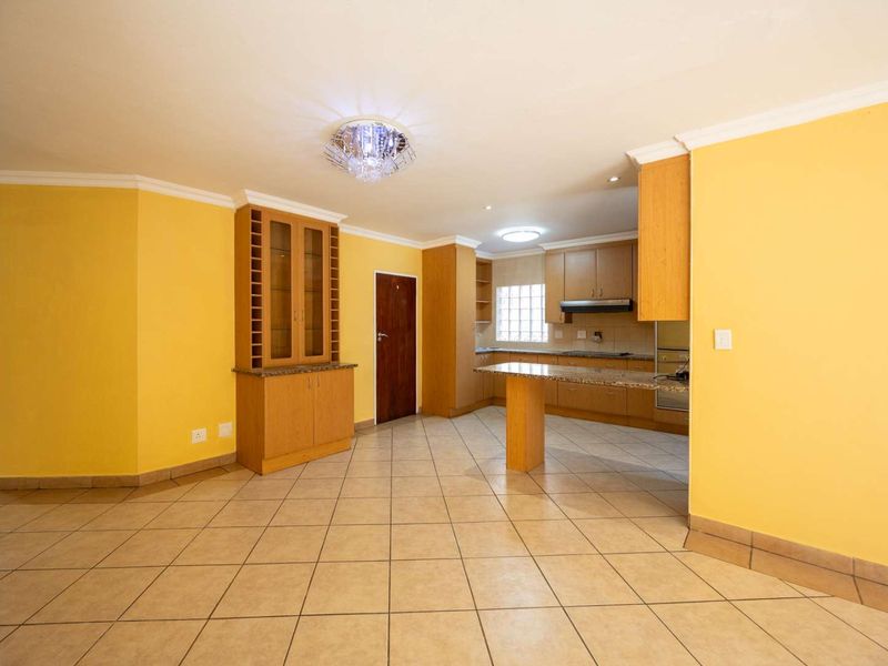 Spacious open-plan kitchen and dining area featuring light wood cabinetry, granite countertops, tiled flooring, and a built-in display cabinet.