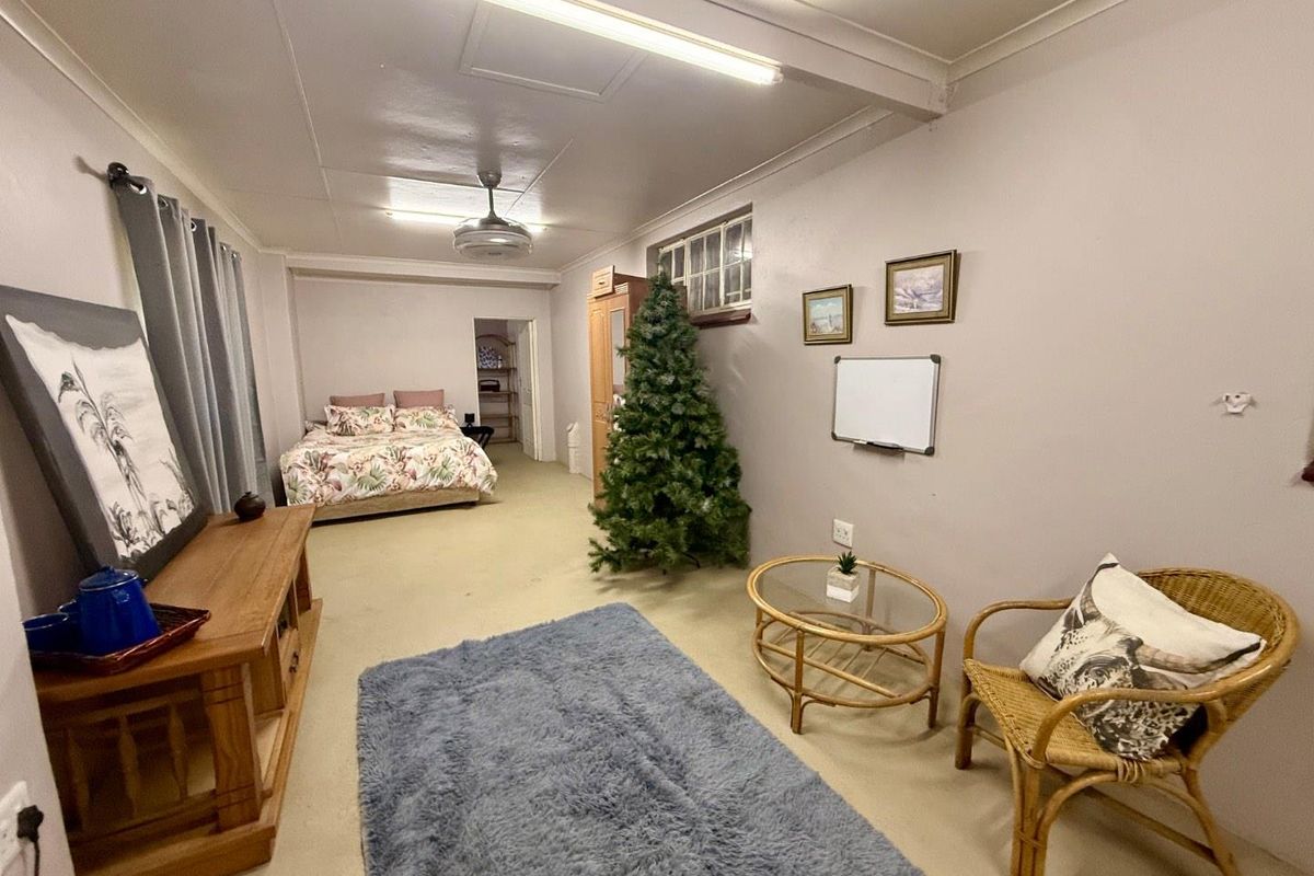 A spacious bedroom featuring neutral walls, carpeted flooring, and functional overhead fluorescent lighting, offering a versatile layout for various furniture arrangements.