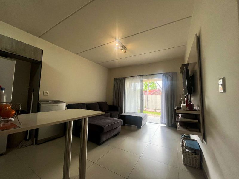 Open plan living area featuring tiled flooring, a built-in shelving unit, and a sliding glass door providing access to the outdoor space.