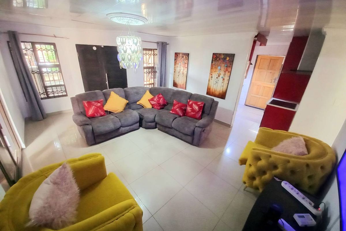 A spacious living area featuring tiled flooring, a decorative ceiling rose, and direct access to adjacent rooms.