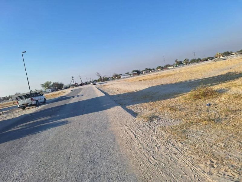 A view of the paved street and adjacent vacant land area.