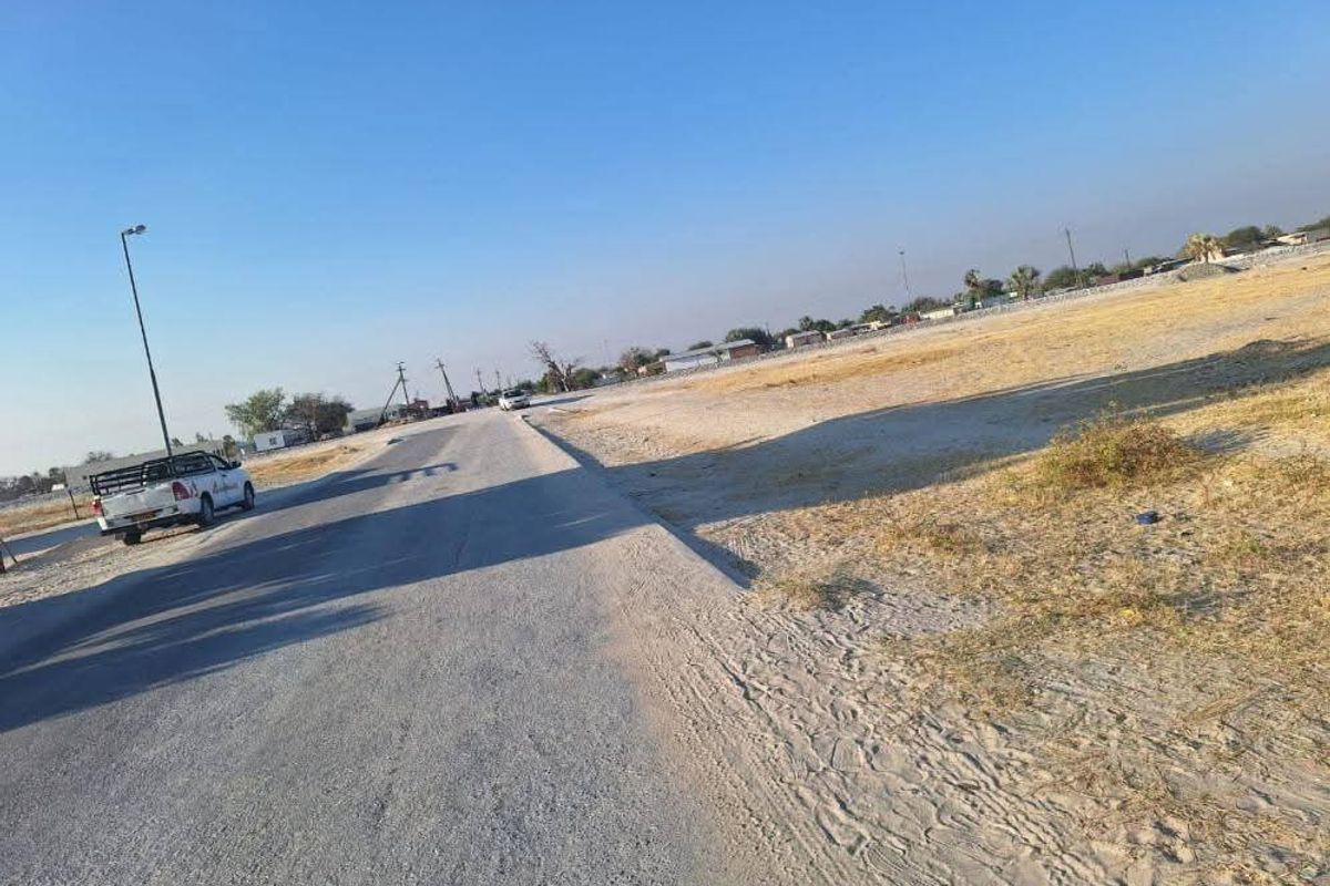 A view of the paved street and adjacent vacant land area.