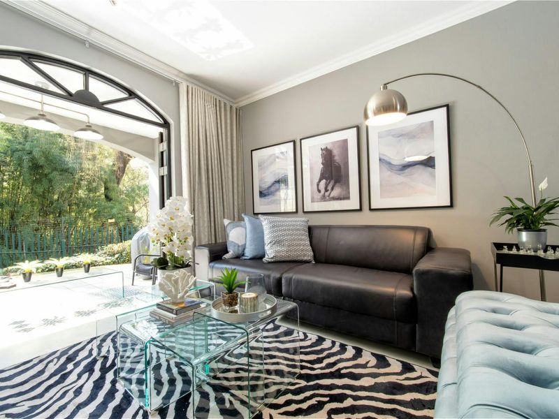 A well-appointed living room featuring elegant crown molding and a large arched glass door providing seamless access to the outdoor patio area.