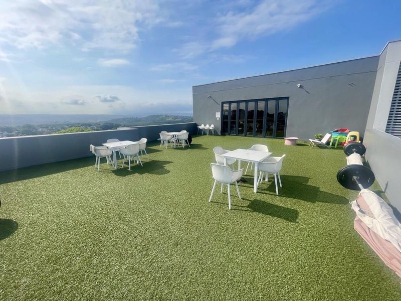 Spacious rooftop terrace featuring artificial turf, modern bi-fold doors, and expansive panoramic views of the surrounding landscape.