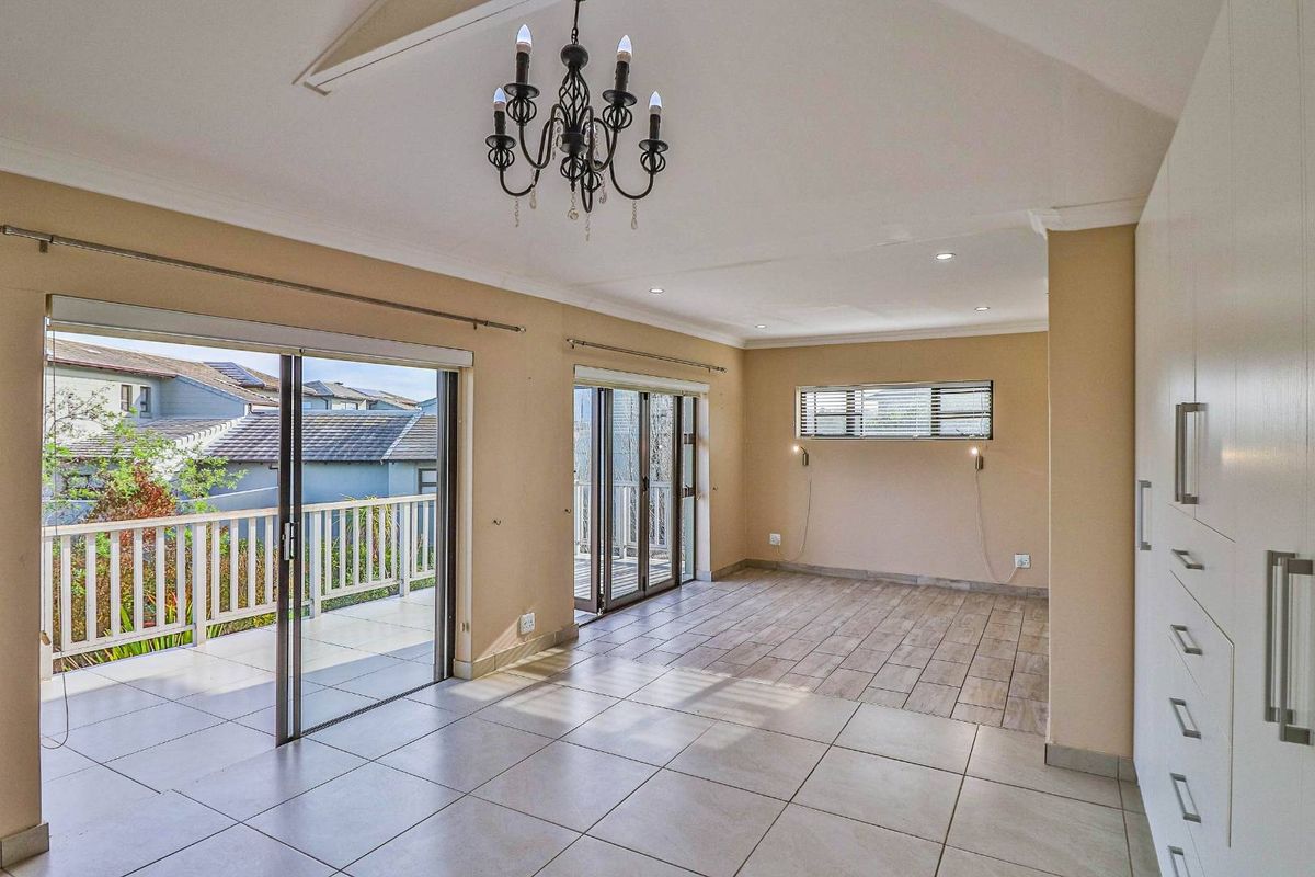 Spacious living area featuring vaulted ceilings, tiled floors, built-in cabinetry, and large sliding glass doors opening onto a private balcony.