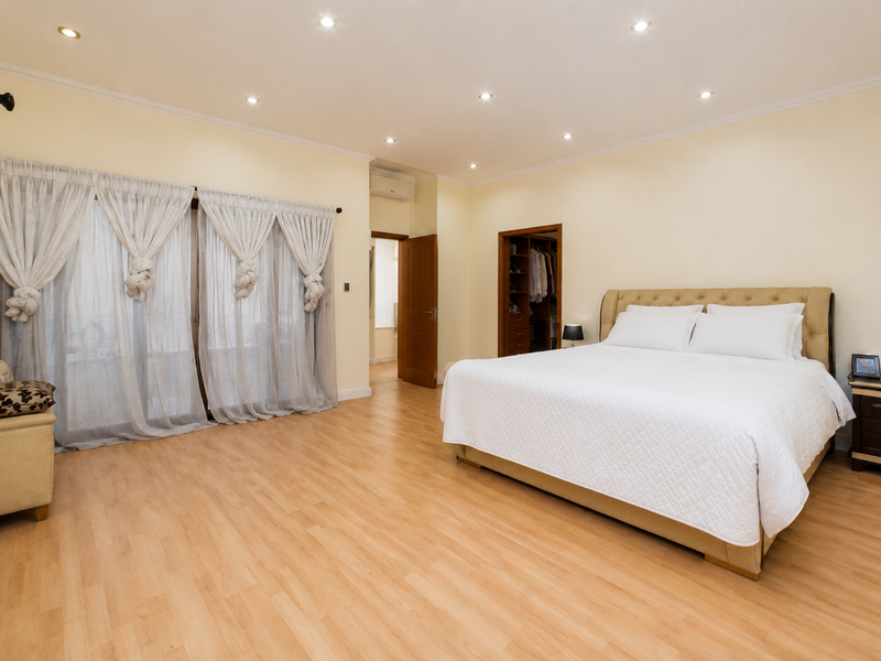 Spacious bedroom featuring light laminate flooring, recessed downlights, a walk-in closet, and sliding glass doors leading to an outdoor area.