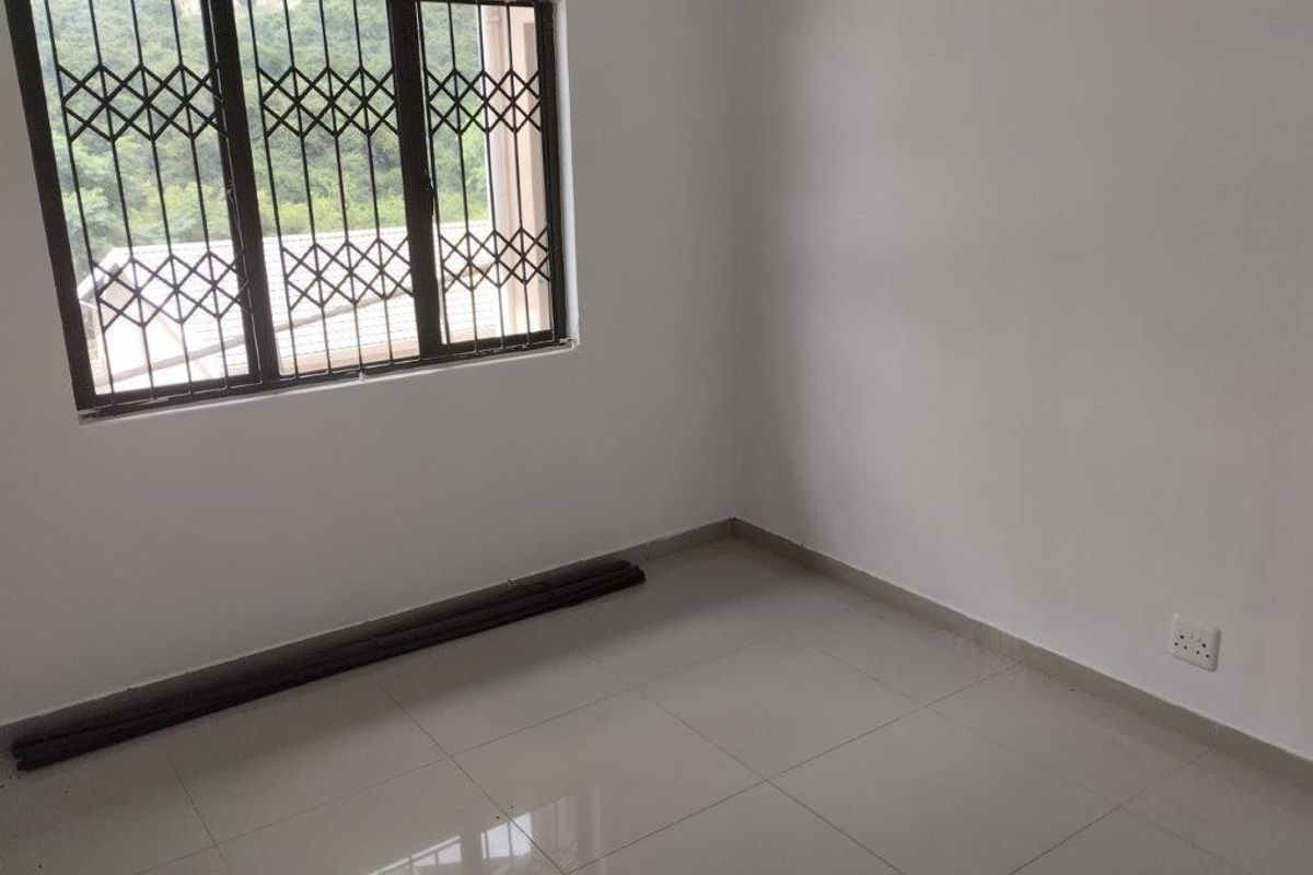 A clean, empty bedroom featuring tiled flooring and a window fitted with a security gate, offering a neutral space ready for personalization.