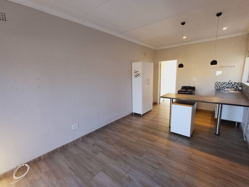 Open-plan living and kitchen area featuring modern tiled flooring, a functional kitchen island, and contemporary pendant lighting.