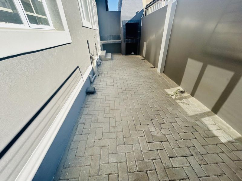 A clean, paved rear courtyard featuring a built-in braai and secure boundary walls, providing a functional outdoor entertainment space.