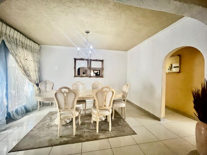 Dining room featuring tiled flooring, a central chandelier, and an arched doorway leading to an adjacent space.