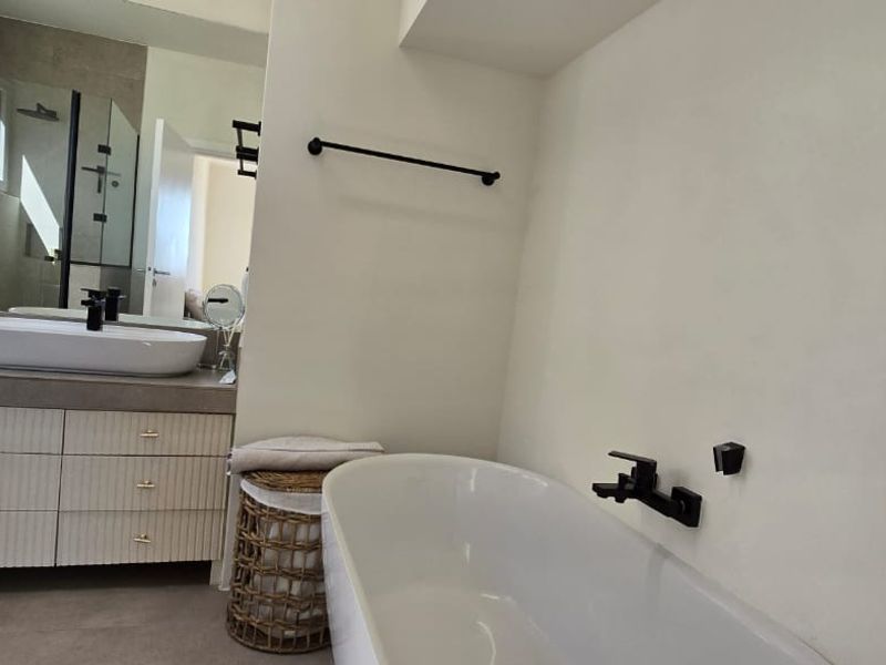 Modern bathroom featuring a sleek vanity with vessel sink, a contemporary freestanding bathtub with wall-mounted fixtures, and a clean, minimalist aesthetic.