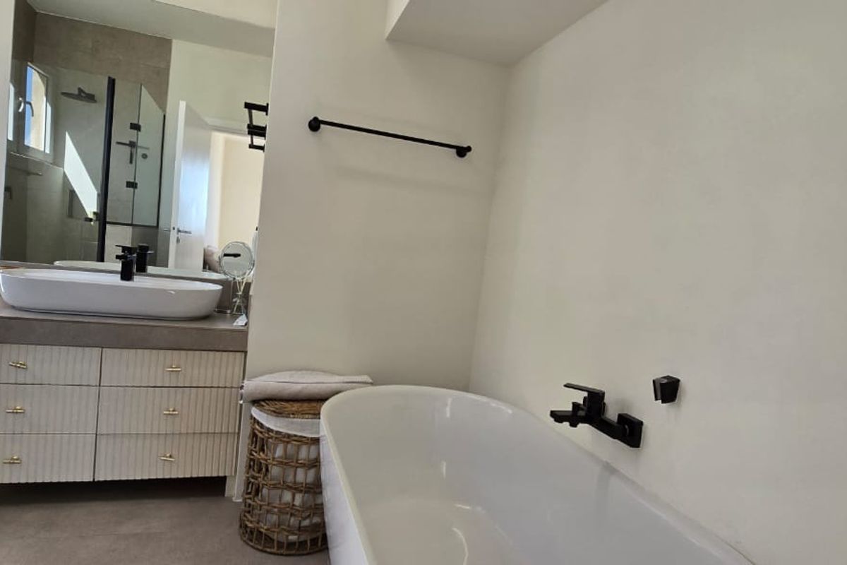 Modern bathroom featuring a sleek vanity with vessel sink, a contemporary freestanding bathtub with wall-mounted fixtures, and a clean, minimalist aesthetic.