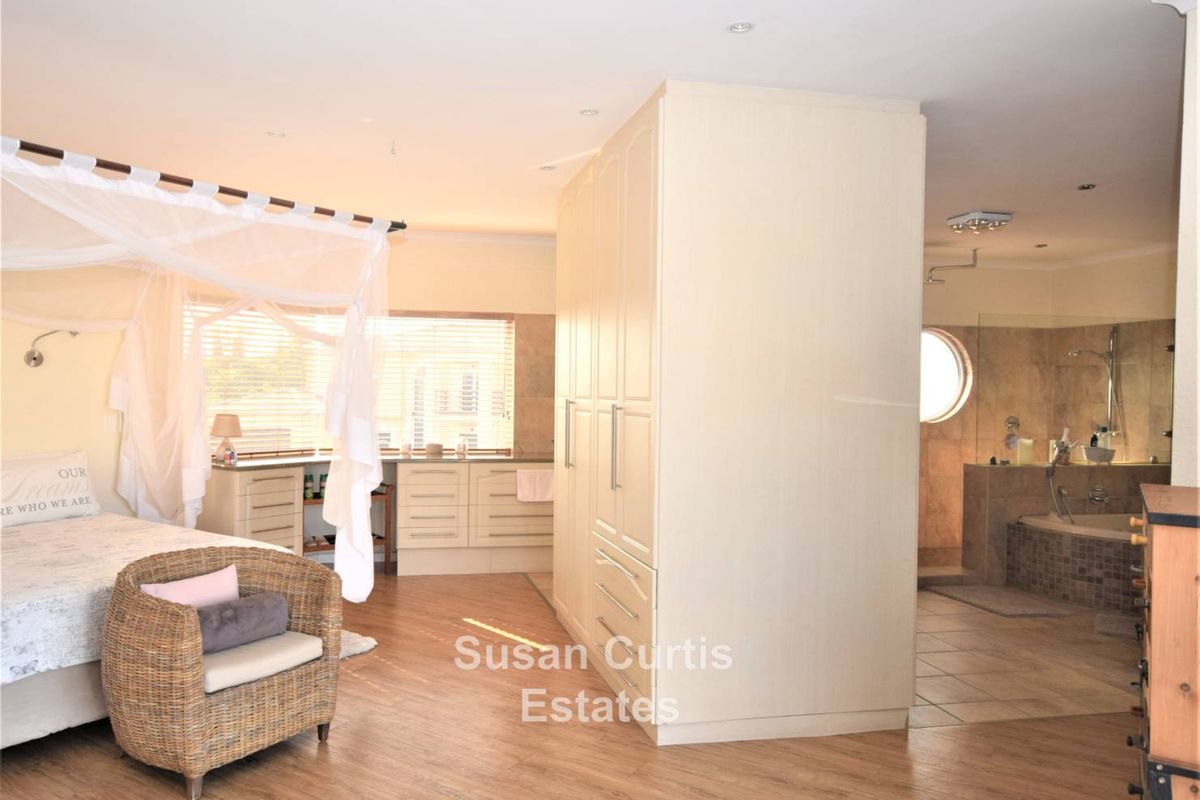 Spacious open-plan bedroom featuring a central built-in wardrobe partition and an integrated en-suite bathroom with a soaking tub and glass-enclosed shower.