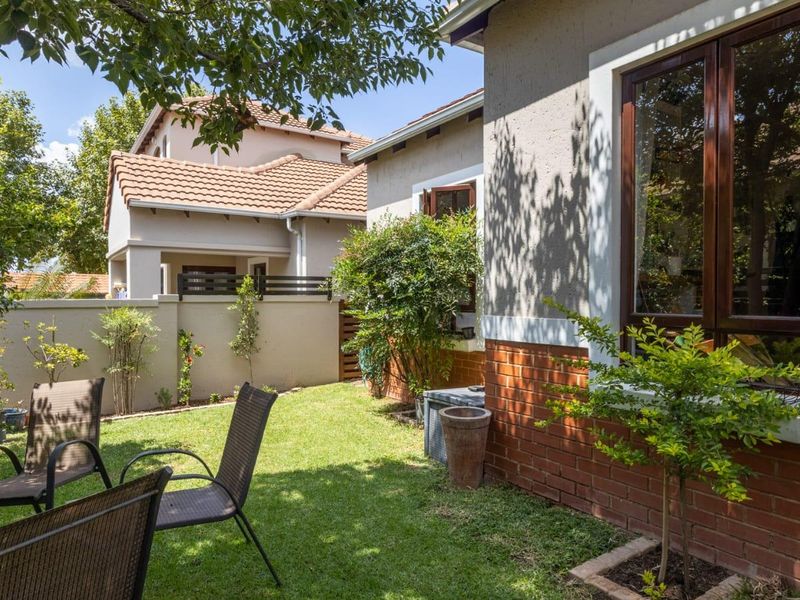 A well-maintained rear garden featuring a lush lawn, brick exterior wall, and timber-framed windows, providing a private outdoor space.