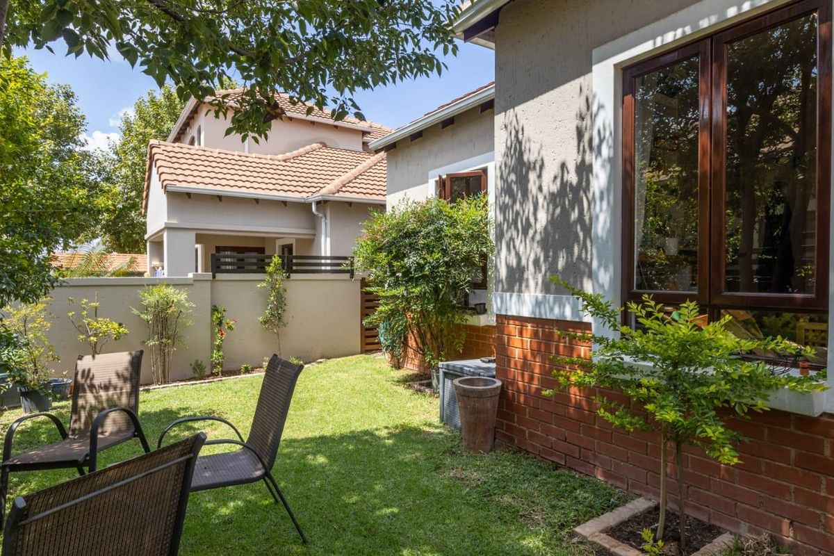 A well-maintained rear garden featuring a lush lawn, brick exterior wall, and timber-framed windows, providing a private outdoor space.