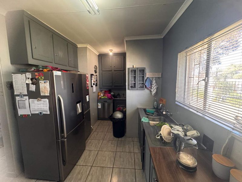 A functional kitchen featuring built-in cabinetry, tiled flooring, and a double sink, offering a practical layout with potential for modern updates.