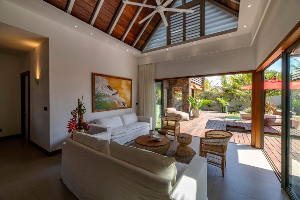 Spacious open-plan living area featuring a high vaulted timber ceiling, recessed lighting, and large sliding glass doors opening onto a wooden deck.