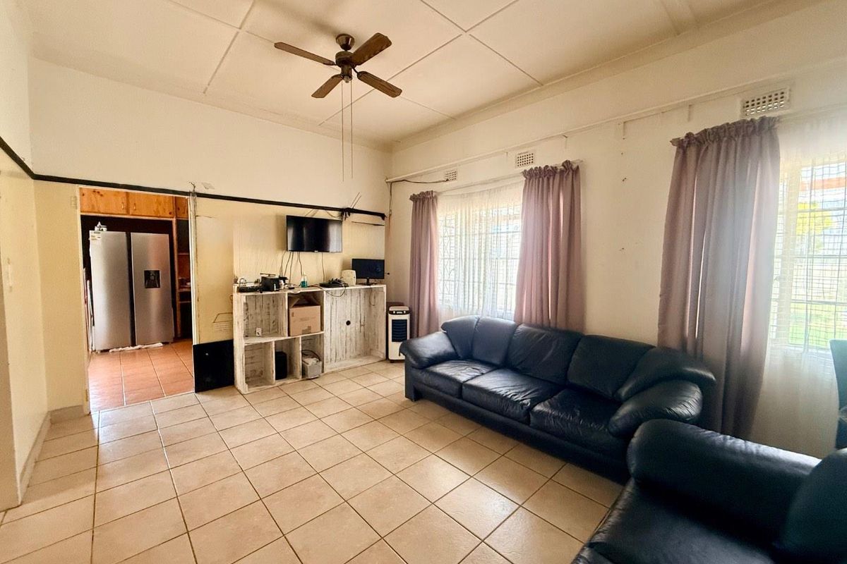 Spacious living room featuring tiled flooring and a ceiling fan, with direct access to the adjacent kitchen area.