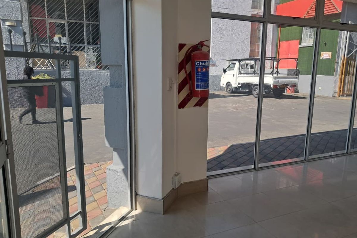 Interior view of a commercial entry area featuring tiled flooring and large aluminium framed glass doors providing access to the exterior.