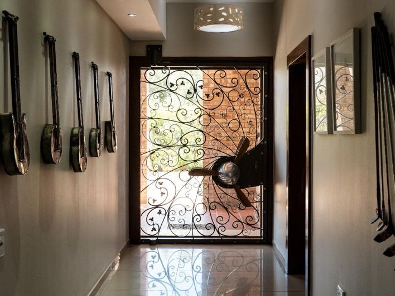 A bright and welcoming entrance hall featuring polished tiled flooring, modern recessed lighting, and a distinctive decorative wrought iron security door.