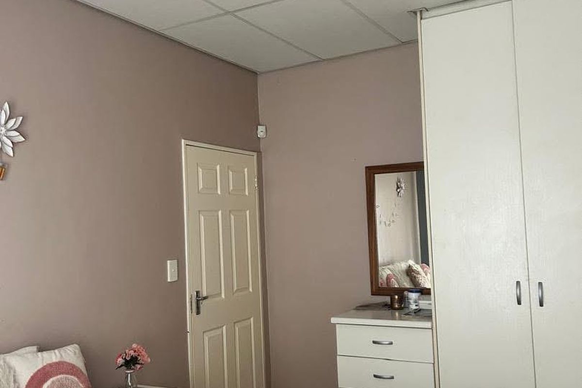 A bedroom featuring built-in wardrobe cabinetry and a drop-ceiling design.