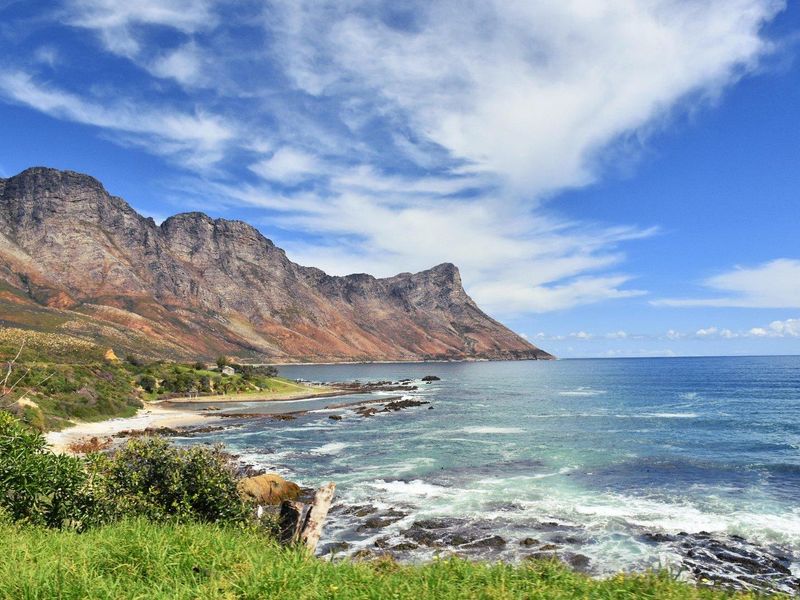 A scenic coastal view featuring rugged mountain ranges meeting the ocean, showcasing the natural landscape and waterfront setting of the property.