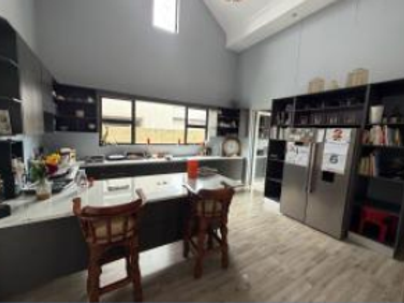 Modern kitchen featuring a large island, extensive built-in cabinetry, stone countertops, and high vaulted ceilings with ample natural light.