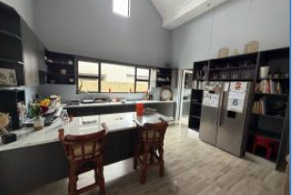 Modern kitchen featuring a large island, extensive built-in cabinetry, stone countertops, and high vaulted ceilings with ample natural light.