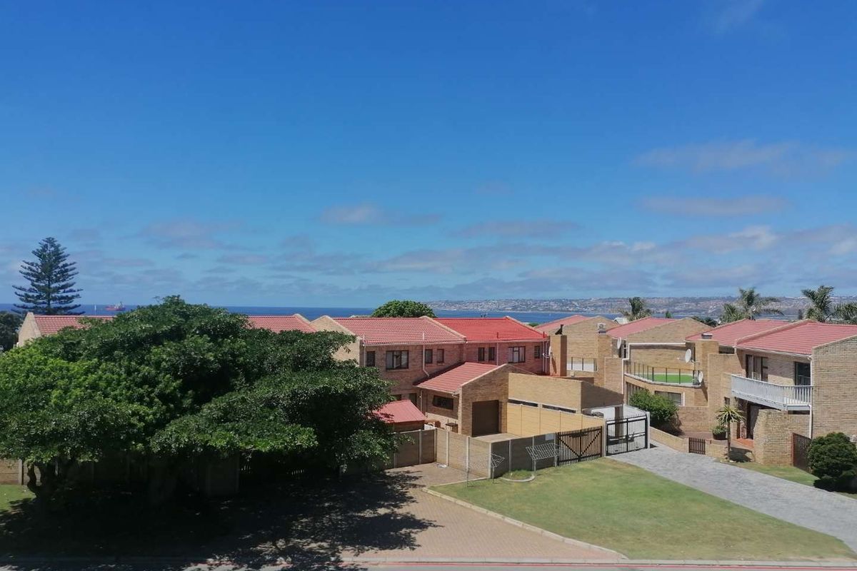An elevated aerial view of a residential apartment complex featuring brick facades, red tiled roofs, paved driveways, and landscaped garden areas.