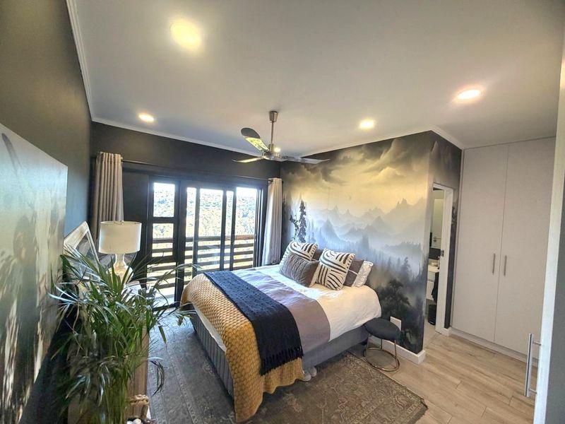 A well-maintained bedroom featuring laminate flooring, built-in cupboards, recessed lighting, a ceiling fan, and a sliding glass door leading to an outdoor area.