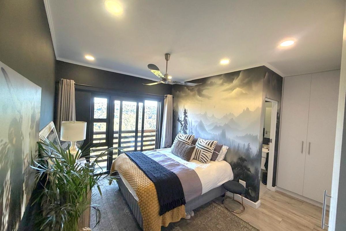A well-maintained bedroom featuring laminate flooring, built-in cupboards, recessed lighting, a ceiling fan, and a sliding glass door leading to an outdoor area.