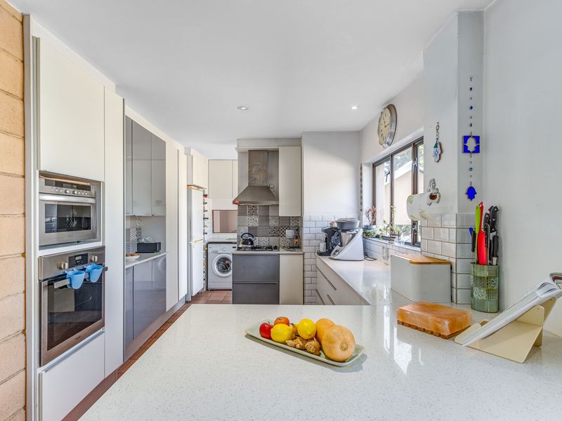 Modern kitchen featuring sleek cabinetry, stone countertops, a tiled backsplash, and integrated appliances including an oven, microwave, and hob.