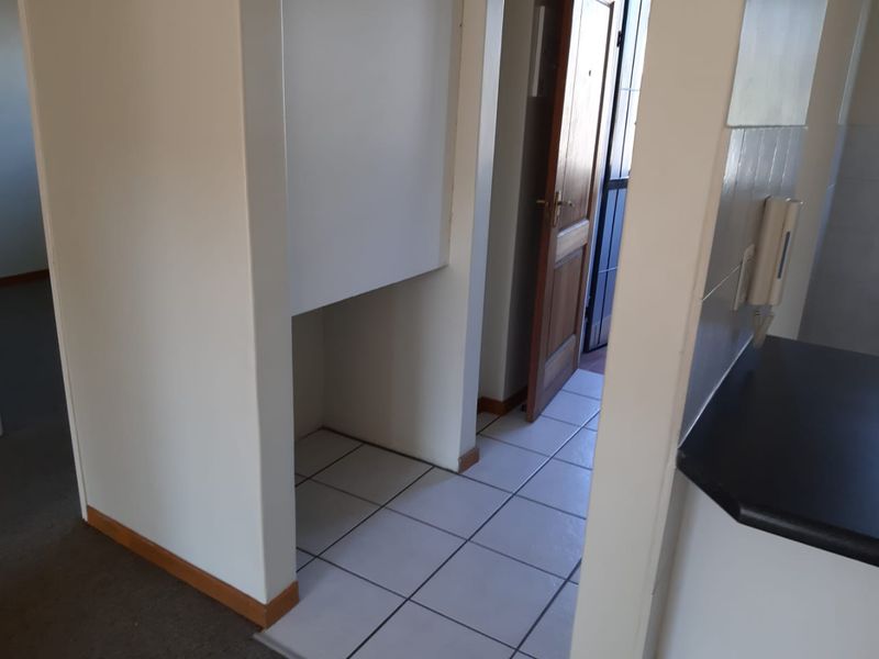 A functional hallway area featuring tiled flooring, a timber entrance door, and a wall-mounted intercom system.